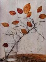a branch with yellow foliage stands outside a wet window photo