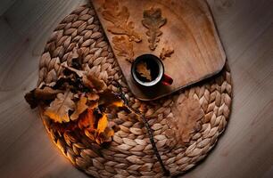 a cup of coffee with an oak leaf stands on a wicker napkin, a twig and a board lie nearby photo