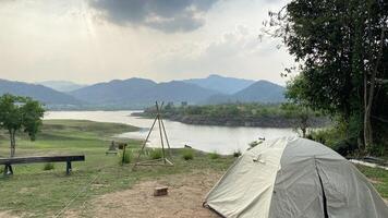 A tent is set up on the grass near a river photo