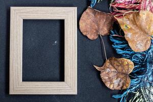 Autumn concept. Top view photo of wooden photo frame of yellow maple leaves and plaid on isolated black background with empty space