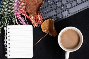 Autumn composition. Cup of coffee, plaid, notepad, autumn leaves on black background. Flat lay, top view, copy space photo