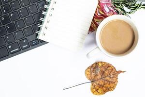 Top view photo of workspace paper sheet envelope on notepad computer mouse cup coffee cup and scarf on isolated gray background with copy space
