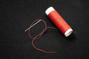 spool of thread with a needle on black isolated background photo