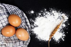Flour and eggs on black table. Cooking process photo