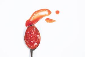 Tomato sauce or ketchup in a spoon, isolated on white background, top view photo
