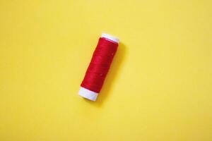 Sewing thread spool, isolated on yellow wbackground. Colored threads are used by factories in the clothing industry. The thread is wound on a spool. Colored scrolls photo