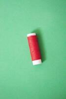 Sewing thread spool, isolated on green background. Colored threads are used by factories in the clothing industry. The thread is wound on a spool. Colored scrolls photo