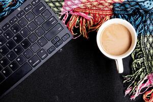 Top view of an autumn freelance work station, complete with laptop, coffee cup, scarf and charming autumn decorations on a black background. Perfect for text or ad placement photo