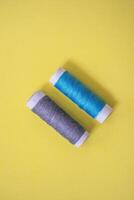 Sewing thread spool, isolated on yellow background. Colored threads are used by factories in the clothing industry. The thread is wound on a spool. Colored scrolls photo