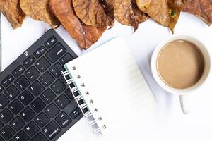 White autumn empty copy space with laptop, coffee, notebook and yellow leaves. Top view. Concept table photo
