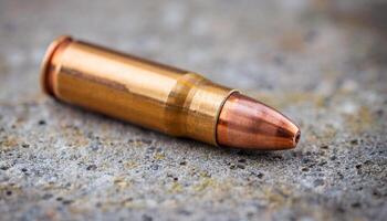 macro view of a bullet casing resting on textured concrete surface with copper tip and shallow depth of field photo