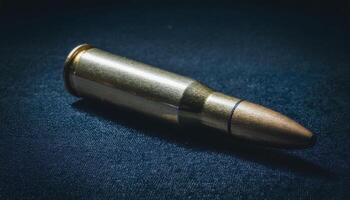close-up view of a single bullet casing with engraved manufacturing details on dark velvet surface under moody lighting photo
