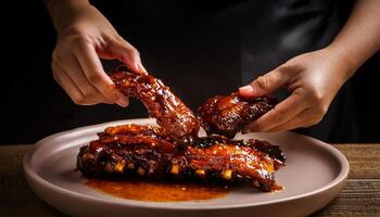 hands pulling apart tender spicy ribs glazed with sticky barbecue sauce, served on a plate with sauce drizzling and rich glaze for food photography photo