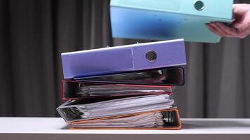 man takes a binder from a stack of colorful ring binders on desk video