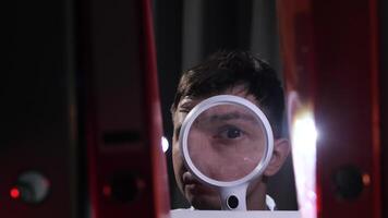 portrait a man in an archive looking through a magnifying glass video