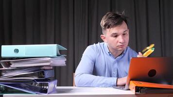 A man works on a laptop in the office and blows on himself with a hand fan video