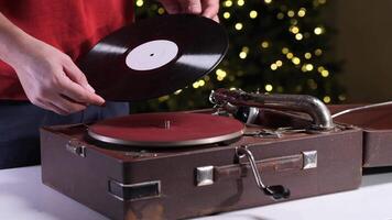 Man putting vinyl record on old gramophone near christmas tree video