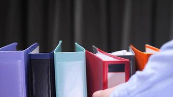 pov close-up Office worker picking a folder from colorful archive shelf video