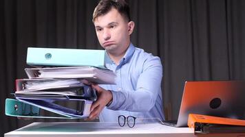 Office worker struggling with stack of binders at desk video
