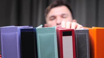A man puts a folder with documents on a shelf. Archive of documents video