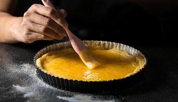 close-up of hands applying egg wash over pie crust in a baking tin, showcasing the glossy golden texture and preparation for baking photo