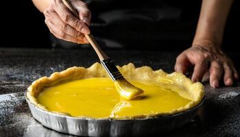 close-up of hands brushing egg wash over pie crust, highlighting the golden shine of the dough and baking preparation process photo