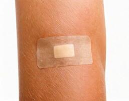close-up of a healing wound with adhesive bandage applied on skin isolated on white background photo
