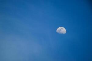 Half moon with blue sky and clouds background during the day. Blue sky background. photo