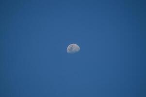 Half moon with blue sky and clouds background during the day. Blue sky background. photo