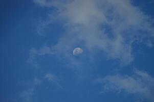 Half moon with blue sky and clouds background during the day. Blue sky background. photo