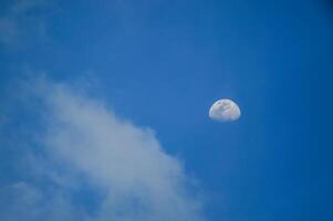 Half moon with blue sky and clouds background during the day. Blue sky background. photo