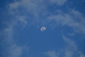 Half moon with blue sky and clouds background during the day. Blue sky background. photo