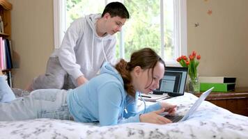 Two young multiracial students study subject using laptop in college classroom. Pair of classmates sitting at desk and chatting together about seminar. Generation z people. Boy and girl. video