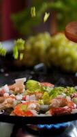 sprinkle shrimp in a frying pan with celery leaves while frying Vannamei shrimp, fried in a pan in boiling oil and sprinkled with spices. Top view close-up. video