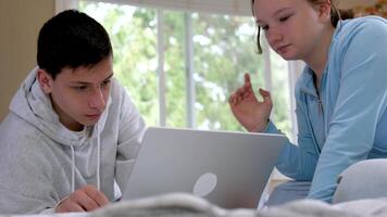College students sitting together at desk and using laptop during computer lesson. Young man and casual girl working together on laptop in high school library or classroom. video