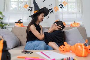Mother and Daughter Enjoying Halloween Activities Together at Home with Costumes and Decorations photo