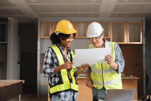 Engineering Team Discussing Construction Plans in Modern Building Site with Blueprints and Safety Gear photo