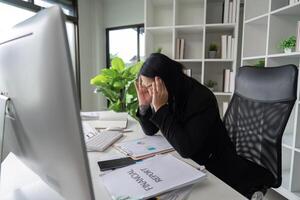 Stressed Business Woman Working at Computer Desk in Modern Office with Financial Reports and Documents photo