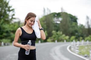 Woman Exercising at the Park with Water Bottle and Towel, Staying Hydrated and Healthy in Outdoor Fitness Routine photo