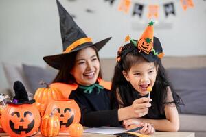 Mother and Child Enjoying Halloween Activities Together in Matching Witch Costumes with Pumpkins and Decorations photo