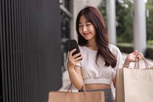 Young Woman Shopping with Paper Bag and Smartphone in Urban Setting, Smiling and Enjoying a Modern Retail Experience photo