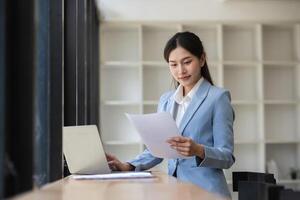 Young Professional Accountant Working in Modern Workspace with Laptop and Documents, Focused and Confident, Business Environment, Office Setting, Financial Analysis, Corporate Attire, Daylight photo