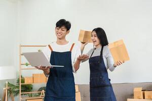 Happy Couple Running a Small Online Business from Home, Managing Orders and Packaging Product, Wearing Aprons, Smiling and Working Together in a Modern Home Office Setting photo