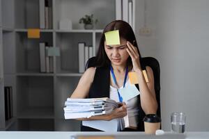Focused Businesswoman Juggling Tasks in Modern Office Setting with Documents and Sticky Notes photo
