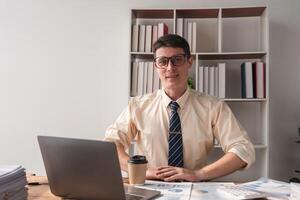 Businessman Working in Modern Office with Laptop, Coffee, and Documents, Professional Male in Formal Attire, Focused on Work, Office Environment, Corporate Setting, Productivity, and Efficiency photo