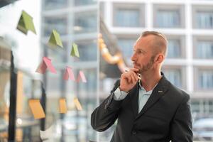 Determined Young Businessman Analyzing Sticky Notes in Modern Office Setting for Strategic Planning and Innovation photo
