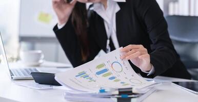 Accountant sitting with financial documents, using laptop, calculating financial and tax figures for company on table in office photo