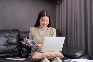 Woman Using Laptop and Reading Document on Sofa. Concept of multitasking and modern work lifestyle. photo