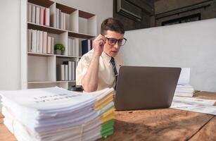 Focused Businessman Working on Laptop in Modern Office with Documents and Files on Wooden Desk, Professional Workspace, Corporate Environment, Productivity, Concentration, Office Work, Business Tasks photo