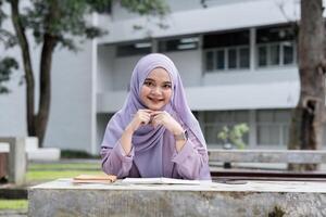 Young Muslim Girl Student in Hijab Studying Outdoors at University Campus, Smiling and Looking Confident, Embracing Education and Knowledge in a Modern Academic Environment photo